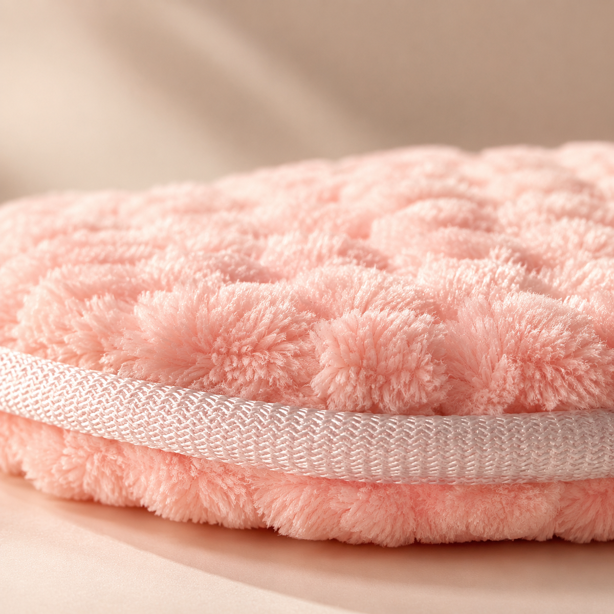 Close up of the soft textured DOLLSFACE® HALO facial cleansing pad with woven edge detail.